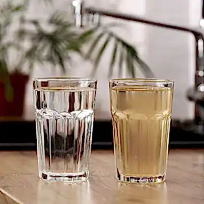 Two glasses on table showing one with clean water and one with dirty water