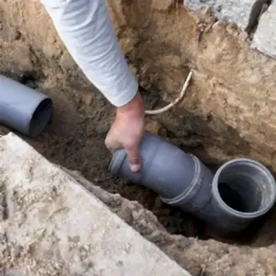 Hand holding on to sewer junction pipe