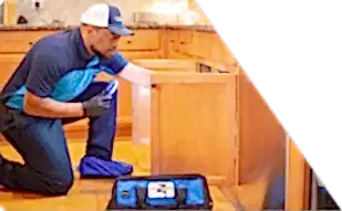 Z PLUMBERS worker kneeling and shining light under cabinet