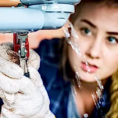 woman using wrench on leaky pipe