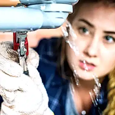 woman using wrench on leaky pipe