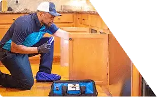 Z PLUMBERS worker kneeling and shining light under cabinet