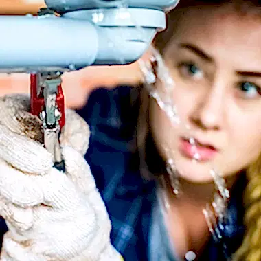 woman using wrench on leaky pipe