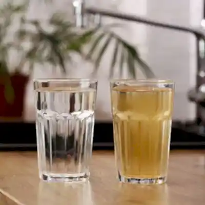 Two glasses on table showing one with clean water and one with dirty water
