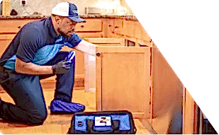 Z PLUMBERS worker kneeling and shining light under cabinet