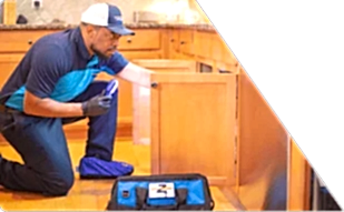 Z PLUMBERS worker kneeling and shining light under cabinet