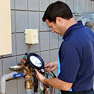 Technician checking sewer backflow gauge