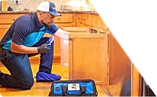 Z PLUMBERS worker kneeling and shining light under cabinet