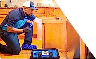 Z PLUMBERS worker kneeling and shining light under cabinet