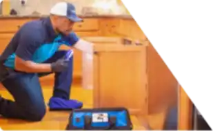 Z PLUMBERS worker kneeling and shining light under cabinet