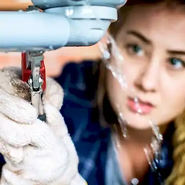 woman using wrench on leaky pipe