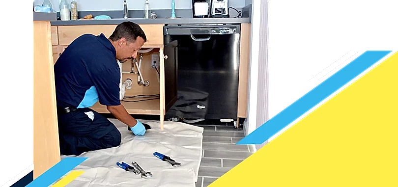 Kneeling Z PLUMBERZ of Auburn Hills technician inspecting a dishwasher