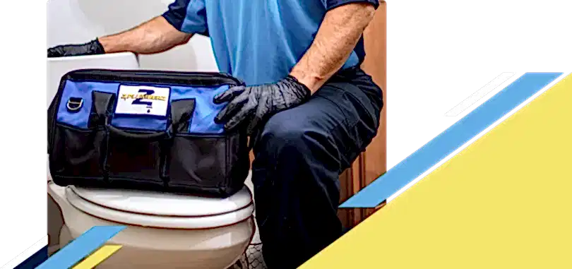 Z PLUMBERZ of Bergen technician kneeling with tool bag on toilet