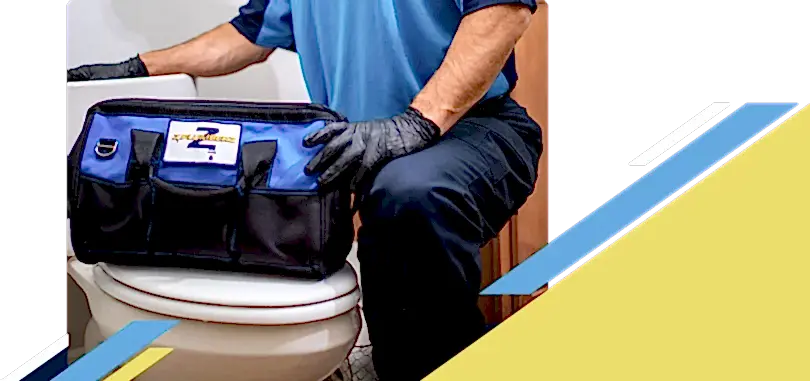 Z PLUMBERZ of Jupiter technician kneeling with tool bag on toilet